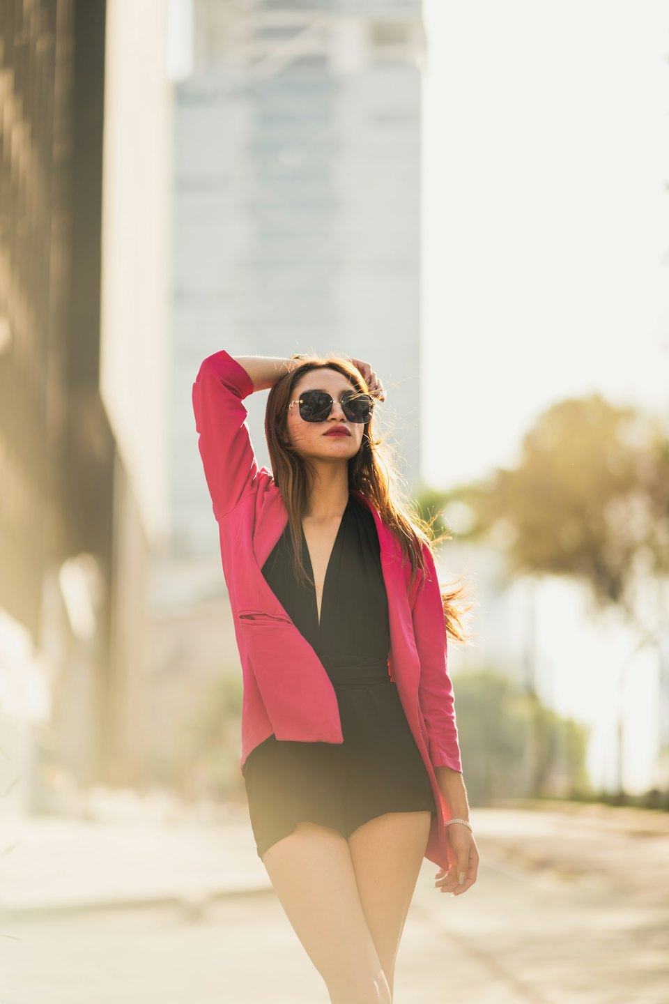 Woman in a fuchsia blazer posing on a city sidewalk.