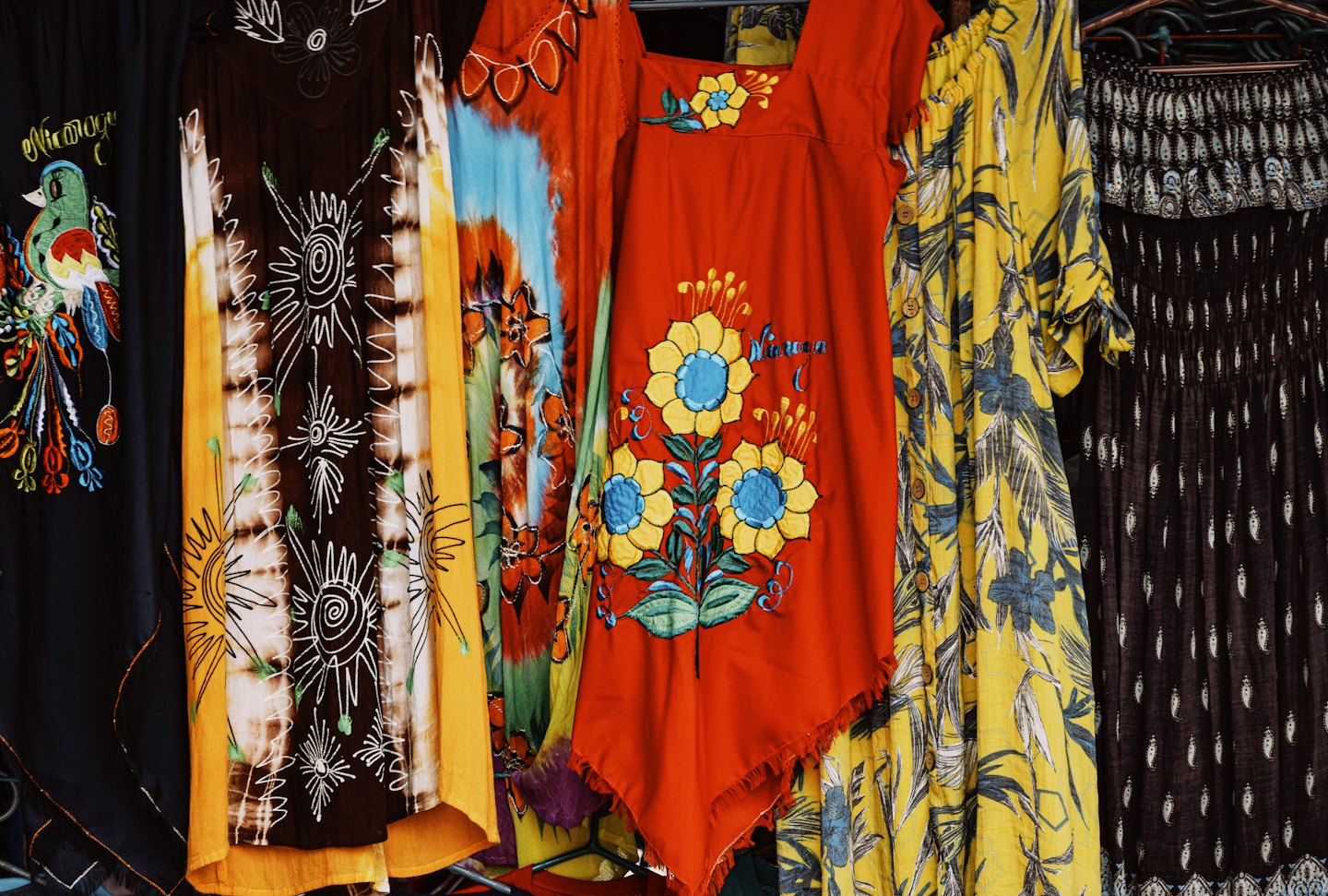 Patterned garments hang together on a clothing rack.